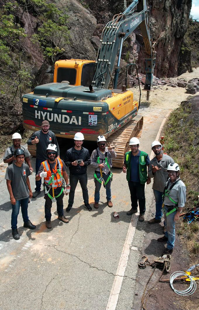 Equipe Real Locação em frente à escavadeira Hyundai 220LC-9 em serra