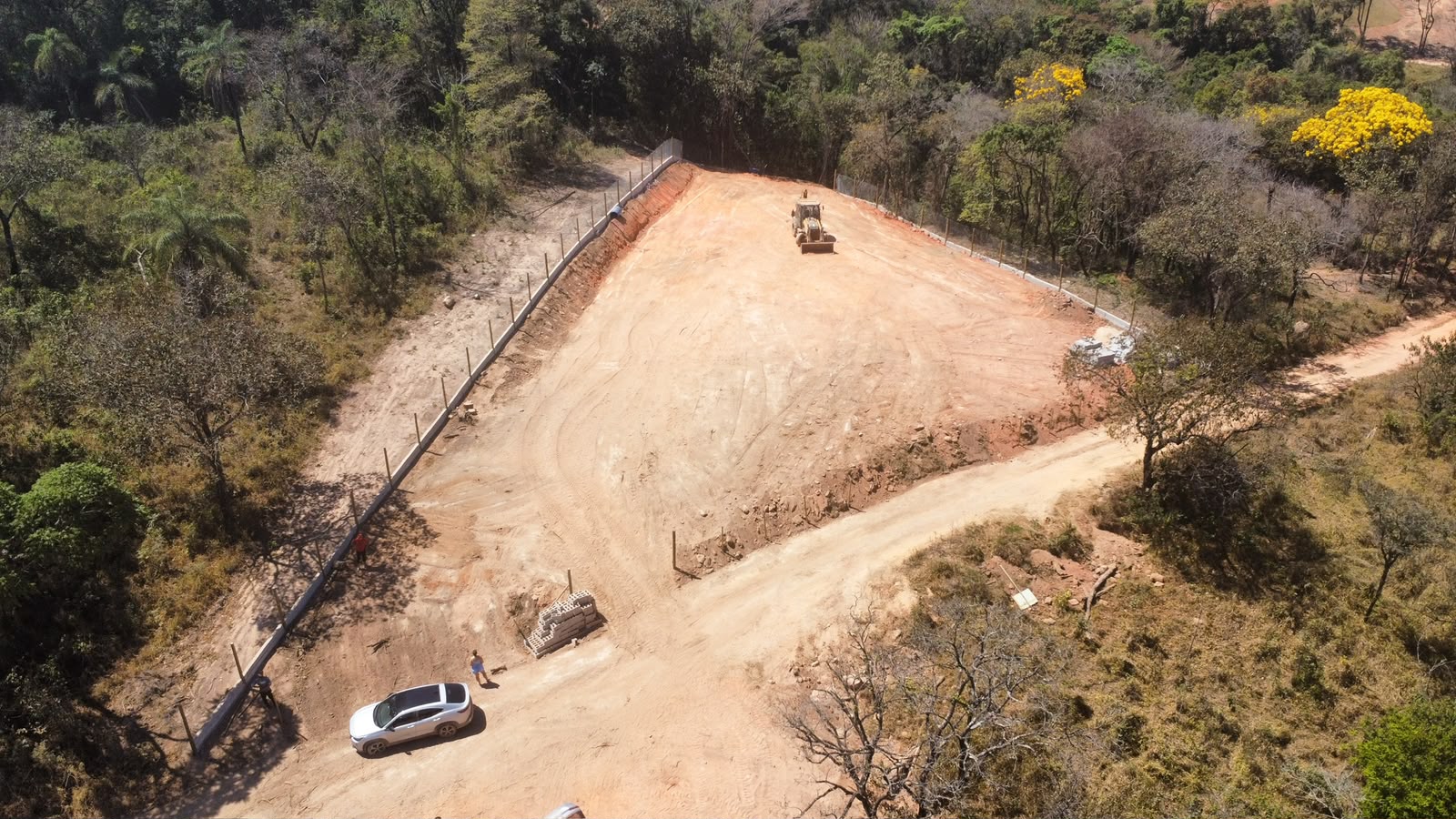 Vista aérea de terraplanagem em terreno com retroescavadeira